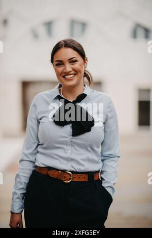 Die lächelnde Latina-Geschäftsfrau schreitet selbstbewusst durch die Straßen der Stadt. Stockfoto