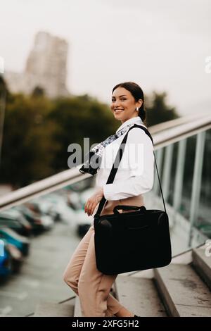 Die lächelnde Latina-Geschäftsfrau schreitet selbstbewusst durch die Straßen der Stadt. Stockfoto