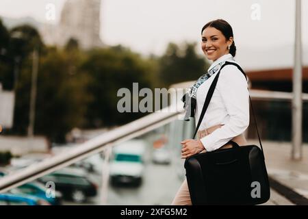 Die lächelnde Latina-Geschäftsfrau schreitet selbstbewusst durch die Straßen der Stadt. Stockfoto