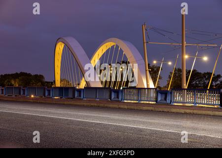 Beleuchtete Straßenbahnhaltestelle mit einer Brücke in Lyon bei Nacht Stockfoto