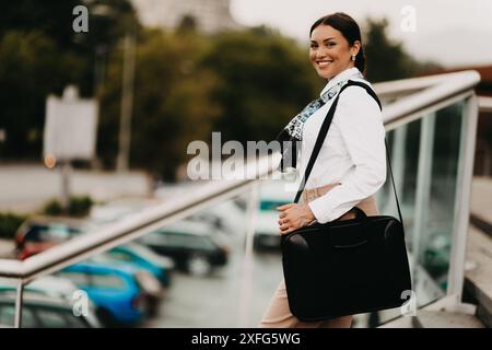 Die lächelnde Latina-Geschäftsfrau schreitet selbstbewusst durch die Straßen der Stadt. Stockfoto