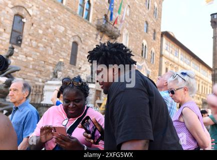 Touristen, die ihre Urlaubsfotos auf Mobiltelefonen in Florenz, Italien, anschauen Stockfoto