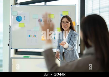 Geschäftsfrau führt eine Präsentation im modernen Büro mit Diagrammen und Diagrammen auf Whiteboard Stockfoto