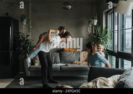 Vater Huckepack-Tochter, während er Freizeit mit der Familie im Wohnzimmer zu Hause verbringt Stockfoto