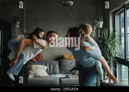 Spielerische Eltern, die Sohn und Tochter im Wohnzimmer zu Hause haben Stockfoto