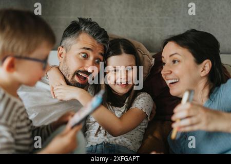 Verspielte Familie, die zu Hause mit Smartphones ihre Freizeit verbringt Stockfoto