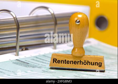 Rentenanpassung und Rentenerhöhung auf einem Aktenordner mit Formularen steht ein Holzstempel mit dem Aufdruck: Rentenerhöhung *** Rentenanpassung Stockfoto