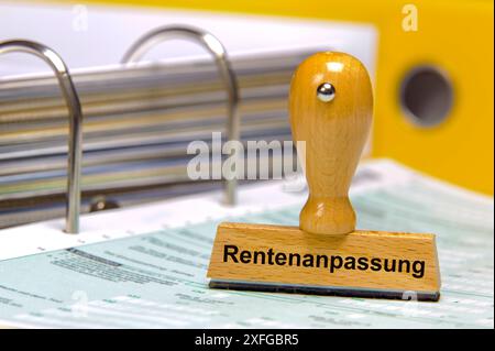 Rentenanpassung und Rentenerhöhung auf einem Aktenordner mit Formularen steht ein Holzstempel mit dem Aufdruck: Rentenanpassung *** Rentenanpassung Stockfoto