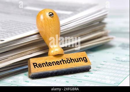 Rentenanpassung und Rentenerhöhung an einem Stapel Formulare lehnt ein Holzstempel mit dem Aufdruck: Rentenerhöhung *** Rentenanpassung und Rente Stockfoto