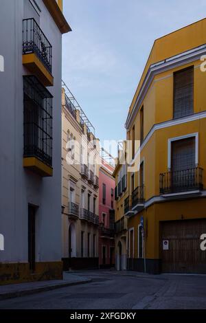 Enge leere Straße mit bunten Gebäuden und Balkonen in Sevilla, Spanien Stockfoto