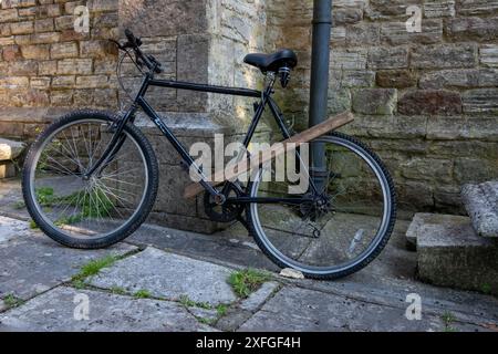 Das schwarze Fahrrad ist ungewöhnlich mit einem Stück Holz verschlossen Stockfoto