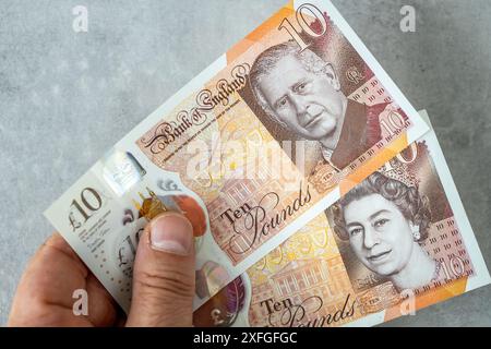 Eine neue £10-Banknote mit einem Porträt von König Karl III., die erstmals im Juni 2024 von der Bank of England in Großbritannien herausgegeben wurde. Gehalten. In seiner Hand, zusammen mit einem Verbot Stockfoto