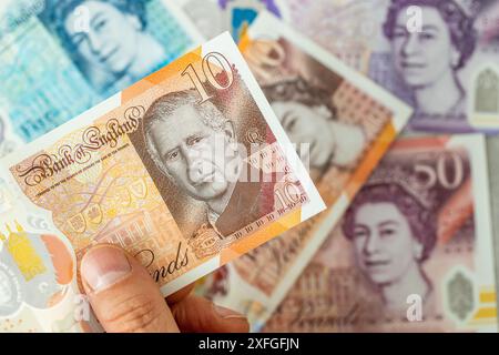 Neue Banknote mit einem Porträt von König Karl III., erstmals im Juni 2024 von der Bank of England, Großbritannien, herausgegeben. Im Hintergrund ältere Banknoten mit dem i Stockfoto