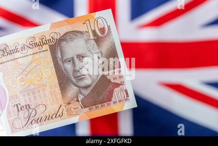 Neue britische Währung mit König Karl III., erstmals im Juni 2024 von der Bank of England in Großbritannien ausgegeben. Die britische Flagge ist im Hintergrund Stockfoto