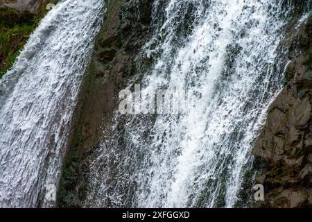 Ein fesselndes Nahfoto eines Wasserfalls, das den dynamischen Fluss und die komplizierten Details des kaskadierenden Wassers zeigt. Stockfoto