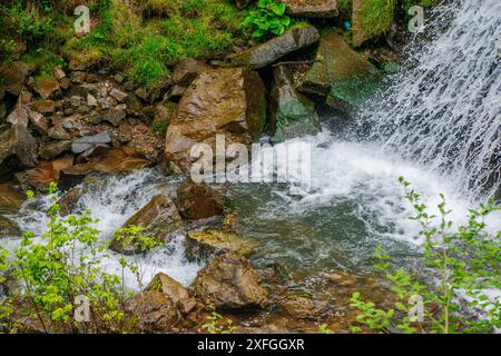 Ein fesselndes Nahfoto eines Wasserfalls, das den dynamischen Fluss und die komplizierten Details des kaskadierenden Wassers zeigt. Stockfoto