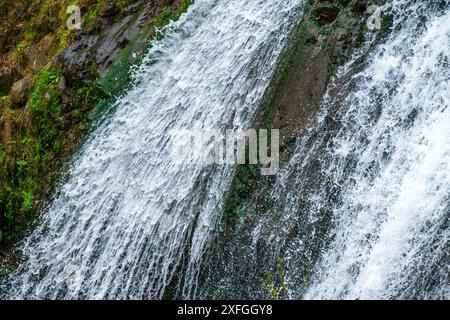 Ein fesselndes Nahfoto eines Wasserfalls, das den dynamischen Fluss und die komplizierten Details des kaskadierenden Wassers zeigt. Stockfoto