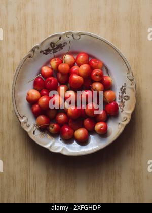 Süße Kirschen auf Einem Beige Vintage Teller auf einem Holztisch. Vertikale Flache Lage. Stockfoto