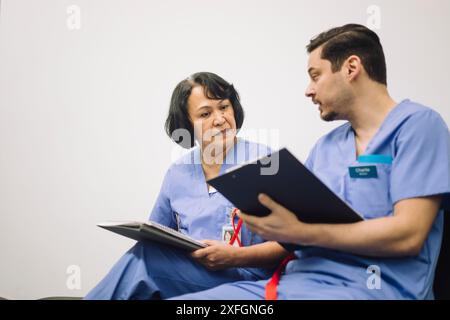 Reifer männlicher Arzt, der mit leitender Ärztin im Krankenhaus diskutiert Stockfoto