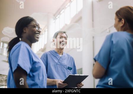 Glücklicher Oberarzt mit weiblichen Kollegen im Krankenhaus Stockfoto