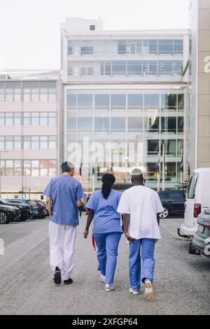 Rückansicht von Ärztinnen und Ärztinnen auf dem Weg zum Krankenhausgebäude Stockfoto