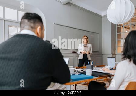 Lächelnde, reife Geschäftsfrau, die sich mit Kollegen im Büro trifft Stockfoto