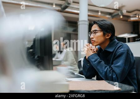 Konzentrierter, männlicher Unternehmer mit Händen, die im Büro auf den Computerbildschirm blicken Stockfoto