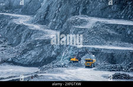 Bagger, der einen Müllwagen in einem mehrstufigen Diabasensteinbruch in Parekklisia, Zypern, beladen Stockfoto