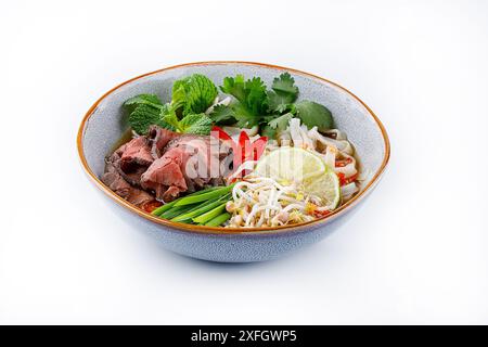 Pho Bo traditionelle Suppe mit Rindfleisch, Reisnudeln, Ingwer, Limette, Chili in einer Schüssel. Nahaufnahme. Vietnamesische und asiatische Küche. Stockfoto
