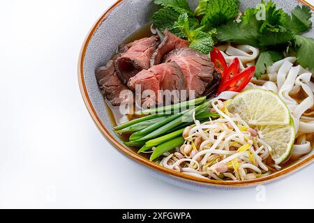 Pho Bo traditionelle Suppe mit Rindfleisch, Reisnudeln, Ingwer, Limette, Chili in einer Schüssel. Nahaufnahme. Vietnamesische und asiatische Küche. Stockfoto