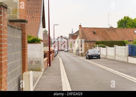 Cambrai, Frankreich - 21. Mai 2023: Eine ruhige Straße in Cambrai, Frankreich, gesäumt von traditionellen Backsteinhäusern und einem Auto, das durch das Zentrum fährt. Stockfoto