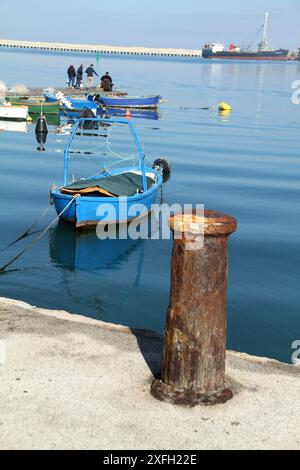 Fischer, Fischerboote und ein metallischer Schiffspoller im Hafen von Molfetta, Italien Stockfoto