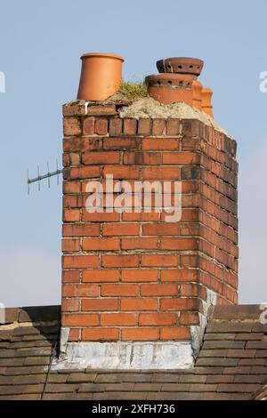 Alter verwitterter Schornsteinstapel mit keramischen Schornsteintöpfen vor klarem blauem Himmel Stockfoto