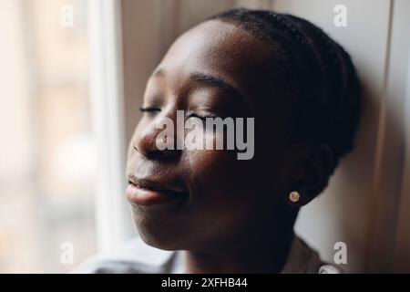 Nahaufnahme eines Teenagers mit geschlossenen Augen in der Nähe des Fensters zu Hause Stockfoto