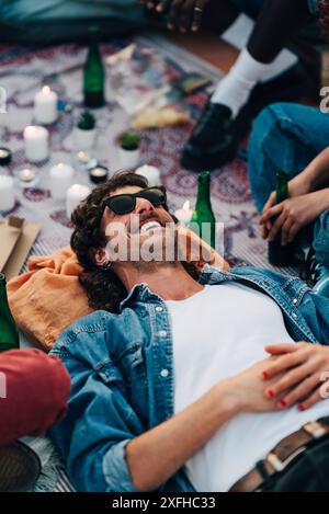 Blick aus einem hohen Winkel auf den lächelnden Mann, der auf einer Picknickdecke auf der Dachterrasse liegt Stockfoto