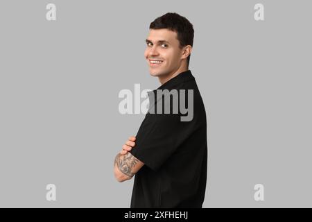 Hübscher junger Mann in stilvollem schwarzen T-Shirt auf grauem Hintergrund Stockfoto