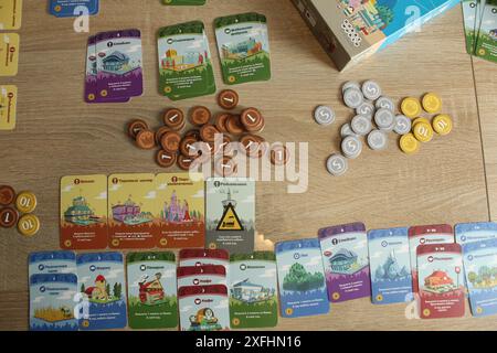 Mozyr, Weißrussland, 10. April 2024: Machi Koro Brettspiel mit Karten und Münzen. Gameplay. Stockfoto