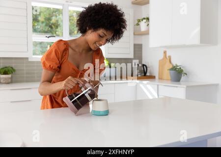 Kaffee aus der französischen Presse in die Tasse gießen, Frau genießt den Morgen in der Küche, Kopierraum Stockfoto