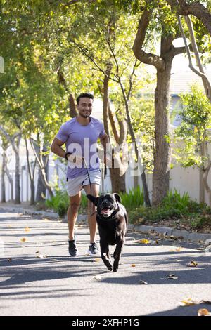 Draußen joggen, Mann läuft mit Hund an der Leine in der Wohngegend Stockfoto