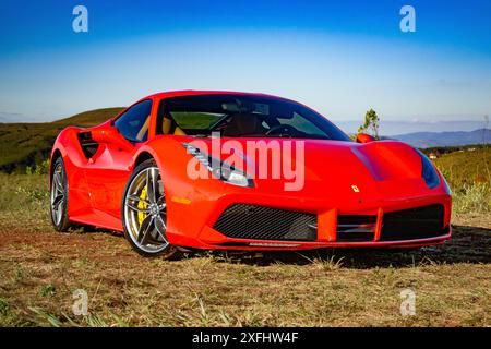 Roter Ferrari 488 GTB auf Gras geparkt, Berglandschaftshintergrund, hohe Auflösung Stockfoto