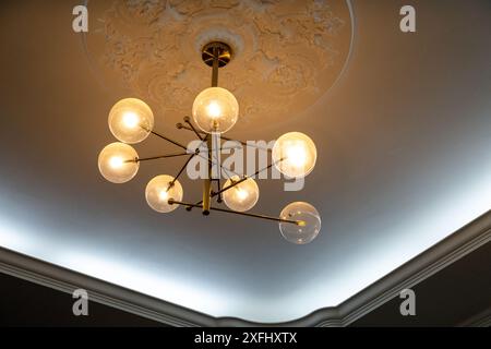 This captivating image showcases a stunning modern chandelier, its sleek design and warm glow adding a touch of elegance to any space. Stock Photo