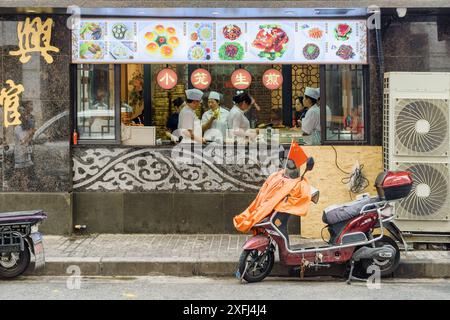 Shanghai, China - 3. Oktober 2017: Blick auf die chinesische Restaurantküche von der Straße. Elektroroller mit der Flagge von China dekoriert. Stockfoto