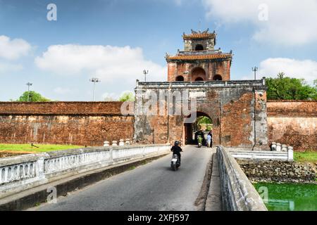 Malerischer Blick auf das Ngan-Tor in der Festungsmauer der Zitadelle und eine Brücke über den Graben rund um die Kaiserliche Stadt mit der lila Verbotenen Stadt, Hue, Stockfoto