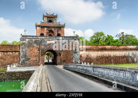 Malerischer Blick auf das Ngan-Tor in der Festungsmauer der Zitadelle und eine Brücke über den Graben rund um die Kaiserliche Stadt mit der lila Verbotenen Stadt, Hue, Stockfoto