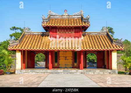 Malerische Aussicht auf das rot-gelbe Hien Duc Gate auf blauem Himmel Hintergrund am sonnigen Sommertag am Minh Mang Grab in Hue, Vietnam. Stockfoto