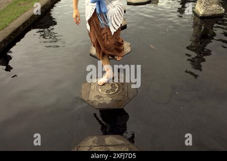 Eine Frau, die im Wasserpalast Tirta Gangga in Karangasem, Bali, auf Steinpfaden läuft. Stockfoto