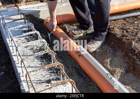 Bauarbeiter, der Kanalrohre in den Fundamenten eines neuen Gebäudes installiert Stockfoto