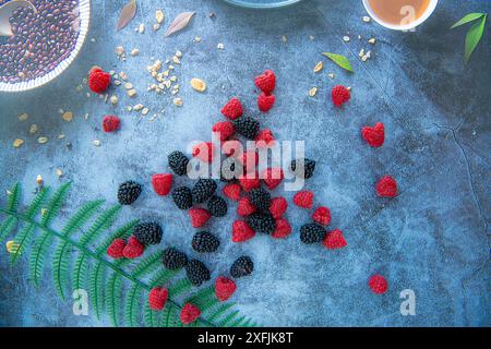 Brombeeren und Himbeeren auf blauem Stein Hintergrund mit Kornflocken herum, isoliert Stockfoto