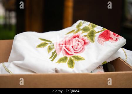 Bestickte Vintage-Tischdecke in einer Pappschachtel. Handgefertigte Tischdecke aus weißer Baumwolle mit Rosenstickerei. Selektiver Fokus. Stockfoto