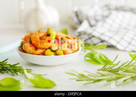 Frischer Salat mit Garnelen und Edamame Sojabohnen in einer Schüssel auf einem weißen Tisch. Stockfoto